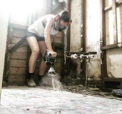 Young woman demolishing slab floor of bathroom for renovation