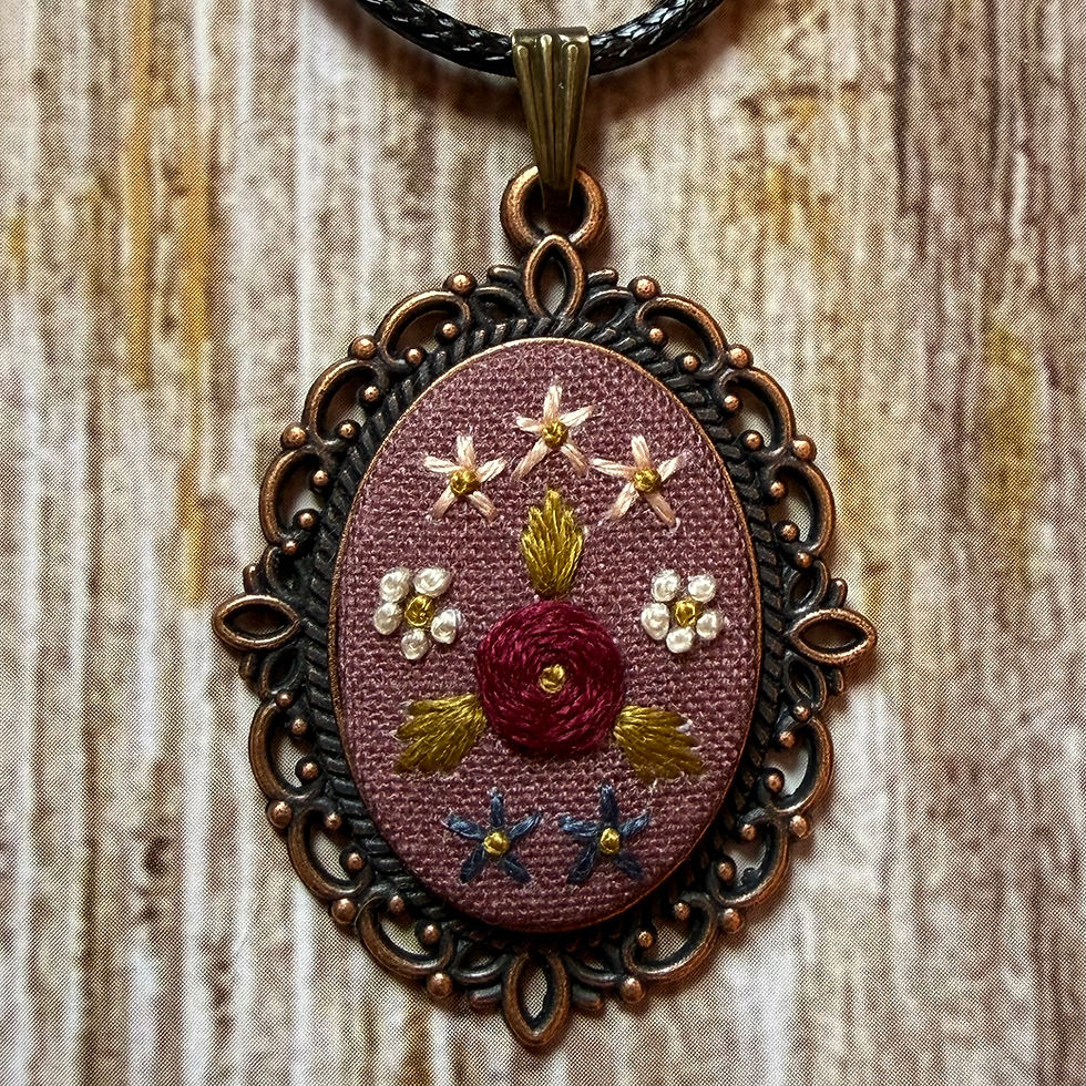 Hand embroidered floral pendant necklace with vintage pink fabric, stitched flowers and an ornate oval bronze frame