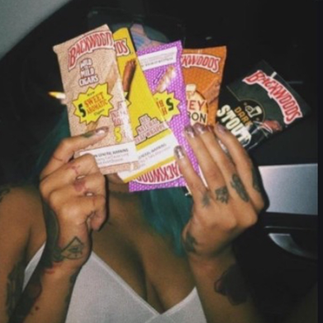 Hands holding multiple Backwoods cigar packs including different flavors, showcasing variety available in smoking culture