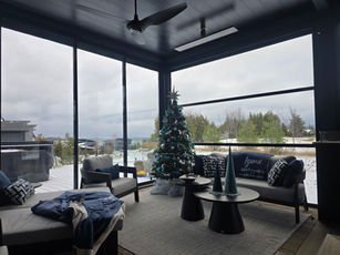 An enclosed deck decorated for the holidays with outdoor heaters and motorized screens