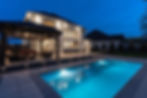 Outdoor renovation with composite decking by a pool at dusk.