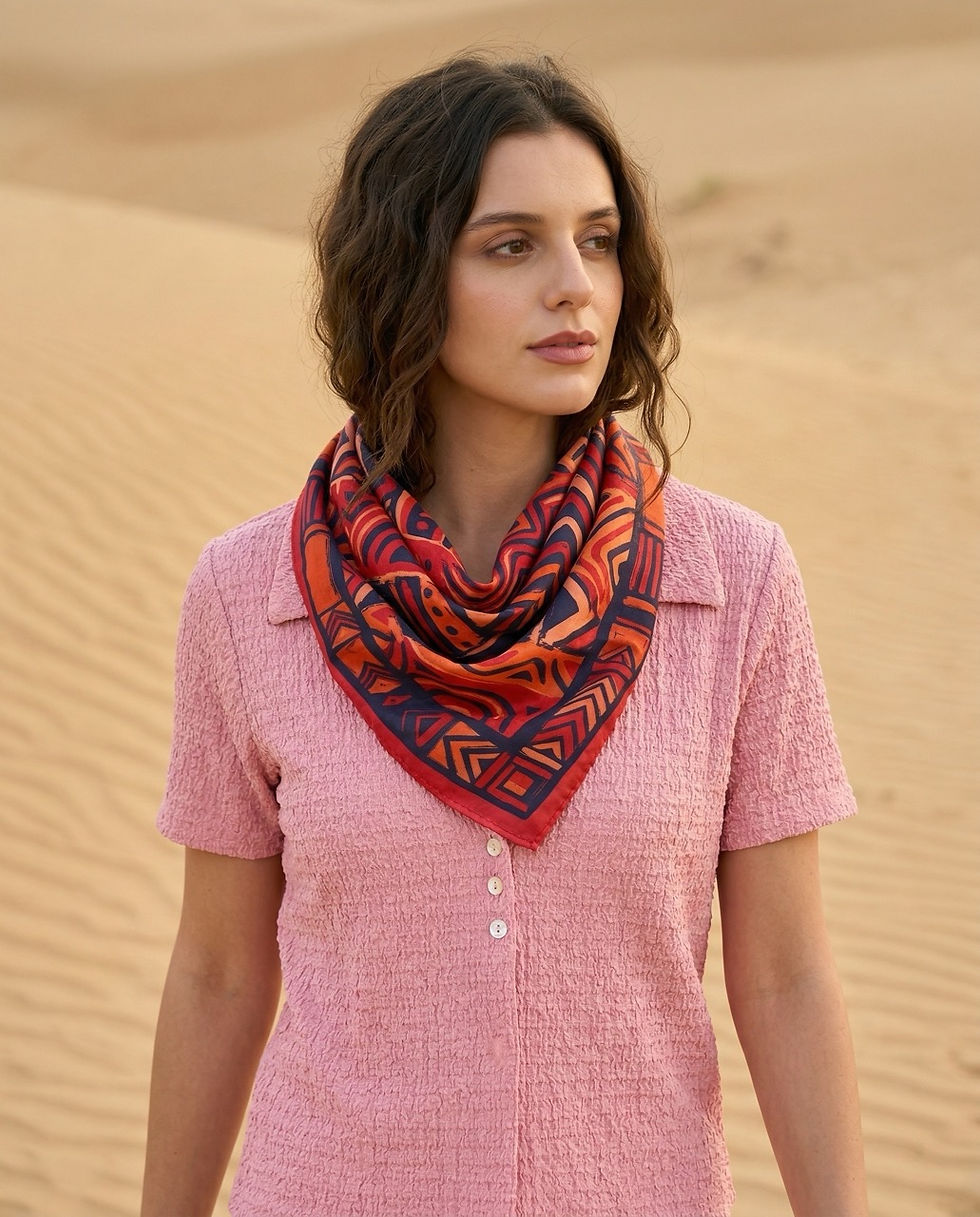 Woman wears red geometric printed scarf around neck