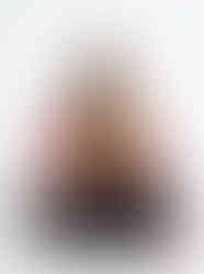 Woman wearing a multicolor tiger-print satin scarf, seated against a plain white background.