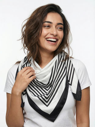 Woman wearing a white satin scarf with black chevron stripes.