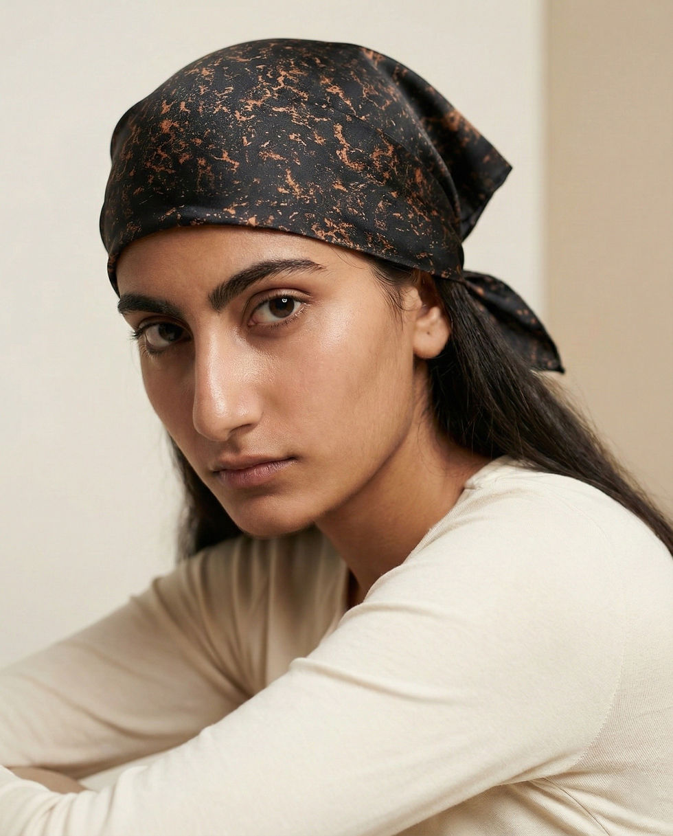 Black and copper abstract satin scarf tied as a head wrap, close view.