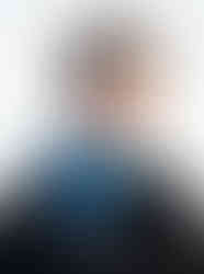 A woman smiling while wearing a blue gradient satin bandana scarf tied in a neat neck knot.