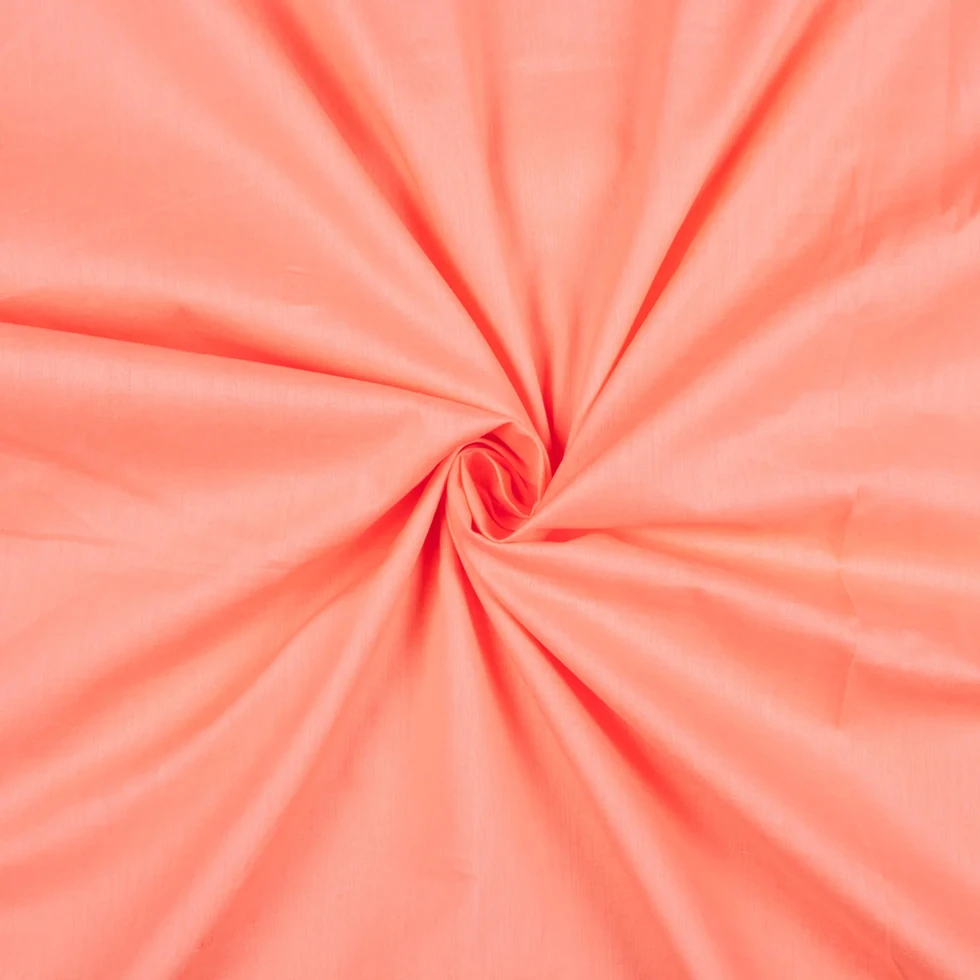 Sunset Coral Plain Cotton Cambric Fabric displayed with a swirl pattern.