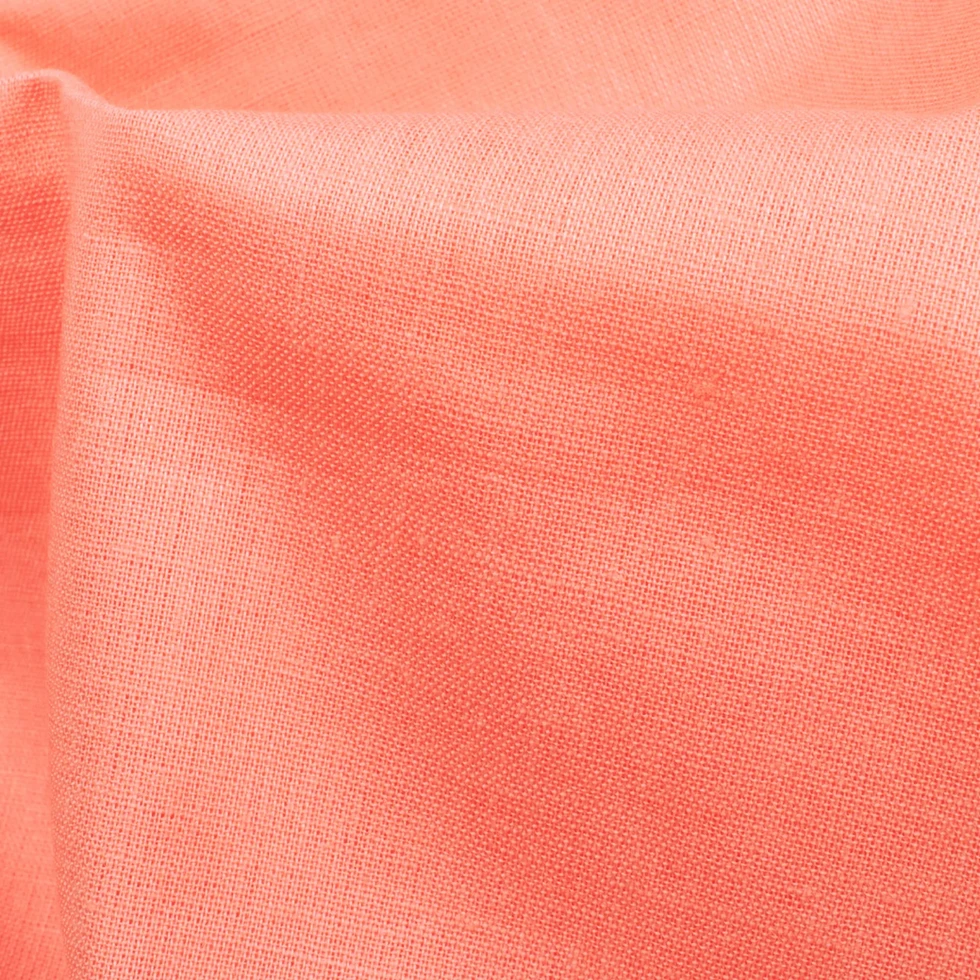 Close-up view of Sunset Coral Plain Cotton Cambric Fabric, showing the fine texture and smooth surface.