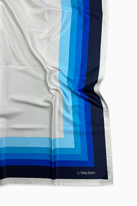 A close-up of a satin scarf with a color block pattern in shades of blue.