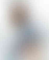 Woman sitting on stool wearing burnt orange abstract square scarf tied around ankle.