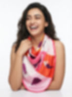 Woman wearing a pink and orange fashion-illustration satin scarf draped around the neck.