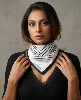 Woman wears black and white geometric satin scarf around neck