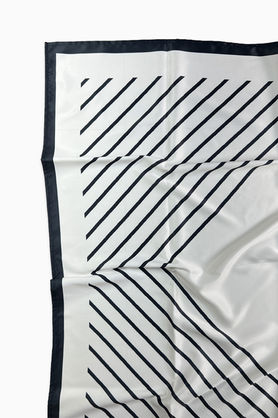 A close-up of a white silk scarf with a black border and diagonal stripes.