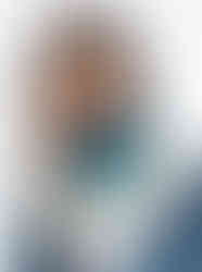 Woman wears teal polka dot satin scarf with yellow border.