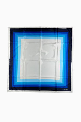 A white square scarf with a color block border of graduating blue shades.