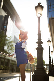 Cinematic portrait by hawaii photographer capturing a woman in a blue cosplay outfit under bright afternoon streetlights. 
