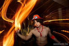 Cinematic portrait by hawaii photographer Grant Uchida capturing a dynamic cosplay scene with light trails of orange light using motion with light painting. One Piece Ace