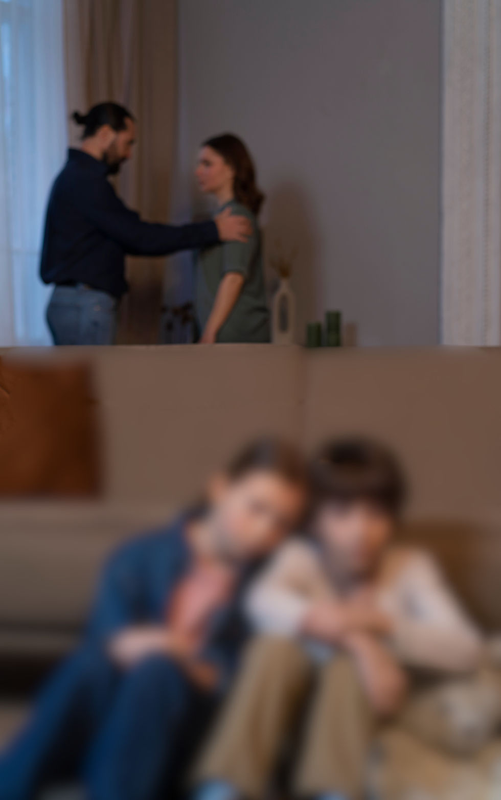 imagem desfocada mostra dois jovens sentados próximos enquanto dois adultos ao fundo parecem estar discutindo