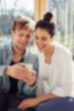 Eine Frau und ein Mann welche auf ein Smartphone schauen und lachen