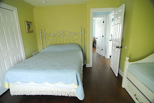 Bed with blue bed spread in a freshly painted green bedroom