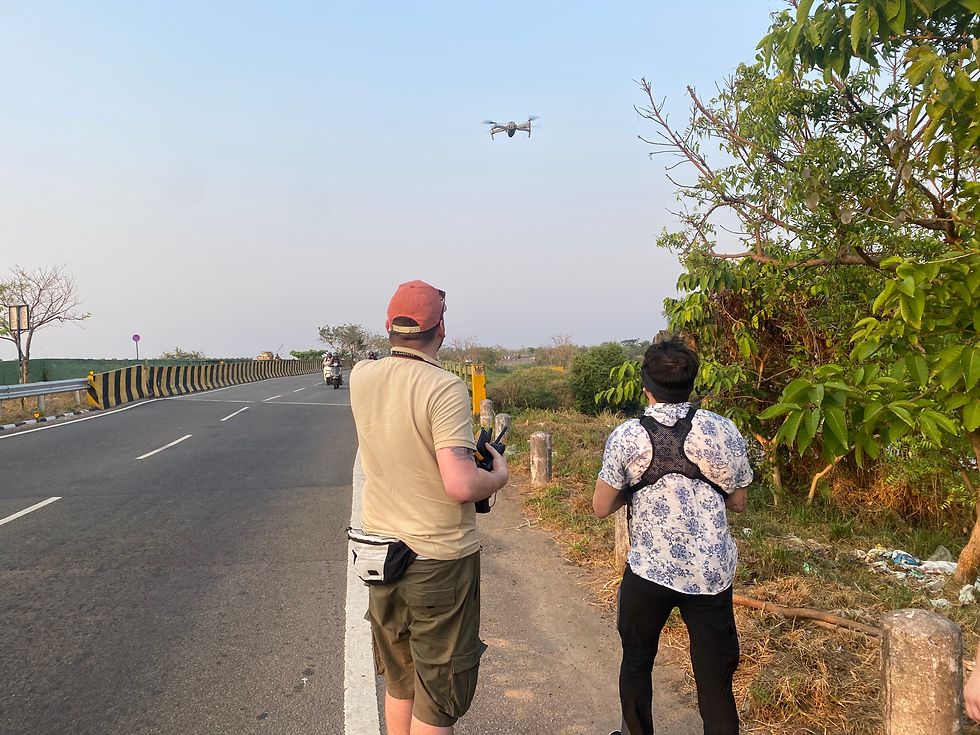 two men flying a drone on a busy indian road