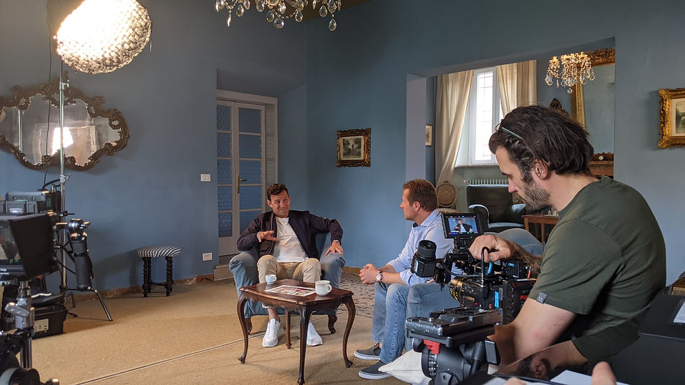 A film crew recording an interview between two men sat in chairs in a grand room