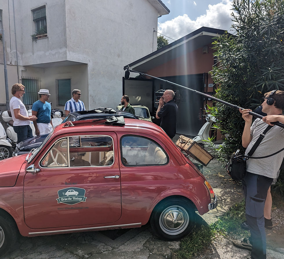 A film crew filming several men stood by a fiat 500