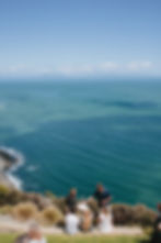 People gathered on a clifftop overlooking the vast blue ocean.