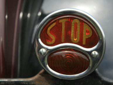 Nicht Nein sagen können: Bremslicht eines Oldtimer-Autos, auf dem das Wort Stop steht