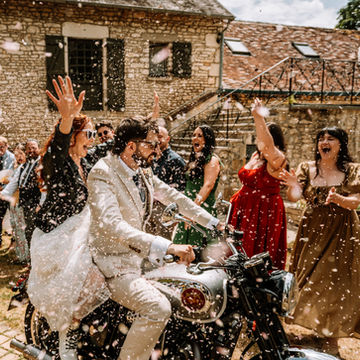 les mariés qui sortent de la cérémonie de en moto avec pleins de confettis