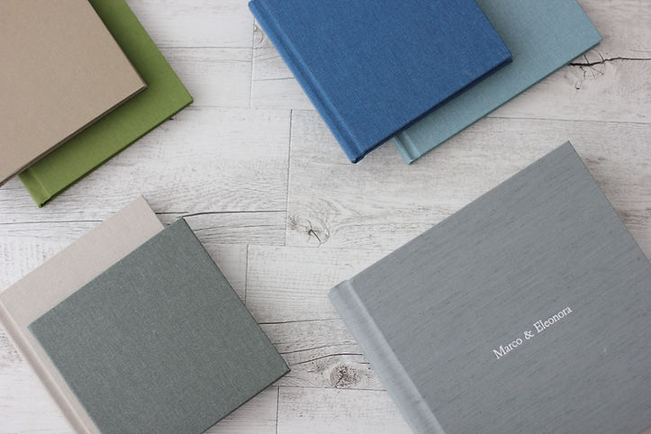 Pairs of books with differently colored covers rest on white wooden table.