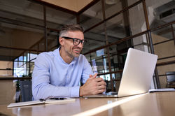 Happy mature business man executive manager looking at laptop computer watching online web