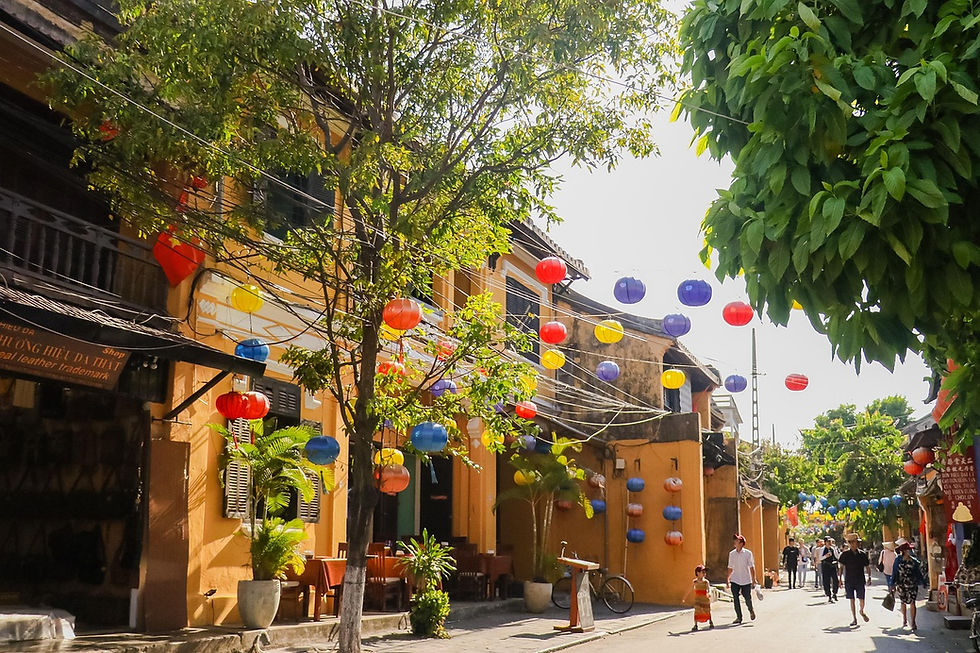 Colorful street scene in Hoi An featuring traditional yellow buildings, hanging lanterns, and tourists walking through one of Vietnam’s most charming cultural and heritage travel destinations.
