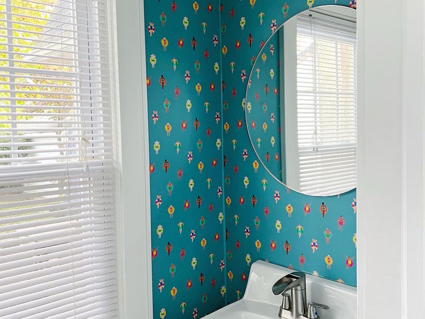 Teal wallpapered powder room with sink and mirror