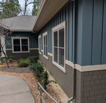 Exterior shot of a blue building with white windows and a sidewalk