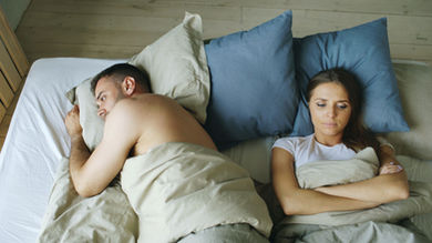 Man turned away from his wife in bed after an argument