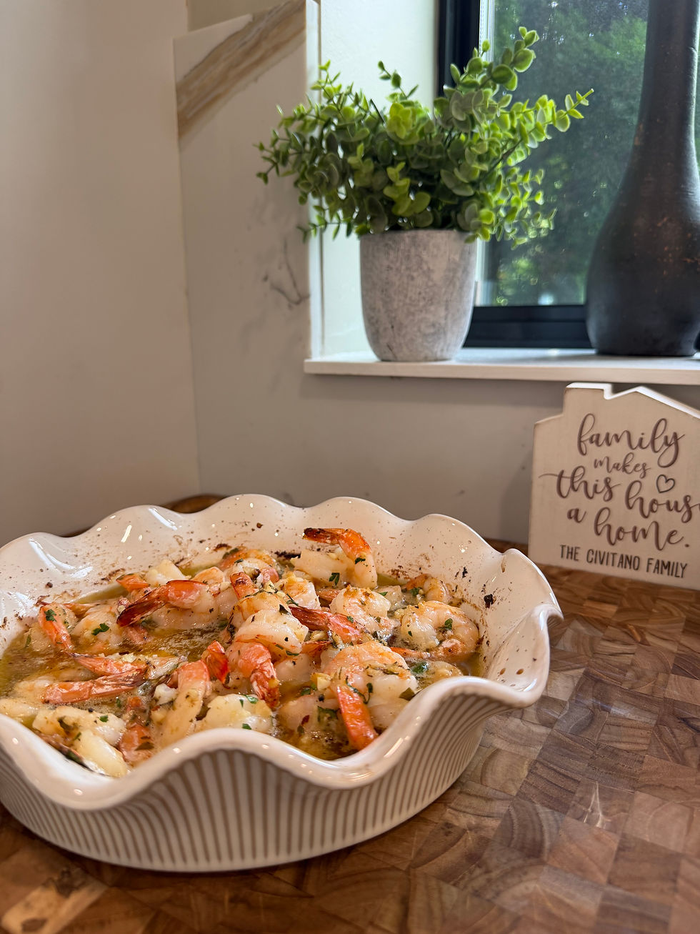 Overhead view of baked shrimp with lemon, parsley, and golden breadcrumbs in a ceramic dish.