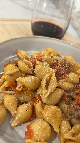 Close-up view of a bowl of pasta shells with bolognese sauce topped with grated cheese and red pepper flakes