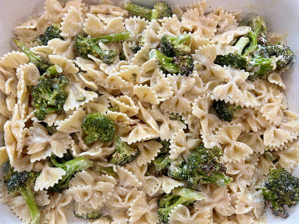 Eye-level view of a bowl filled with creamy roasted broccoli Boursin pasta topped with fresh herbs