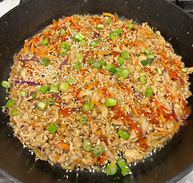 Eye-level view of a skillet filled with cooked ground meat and colorful cabbage mix
