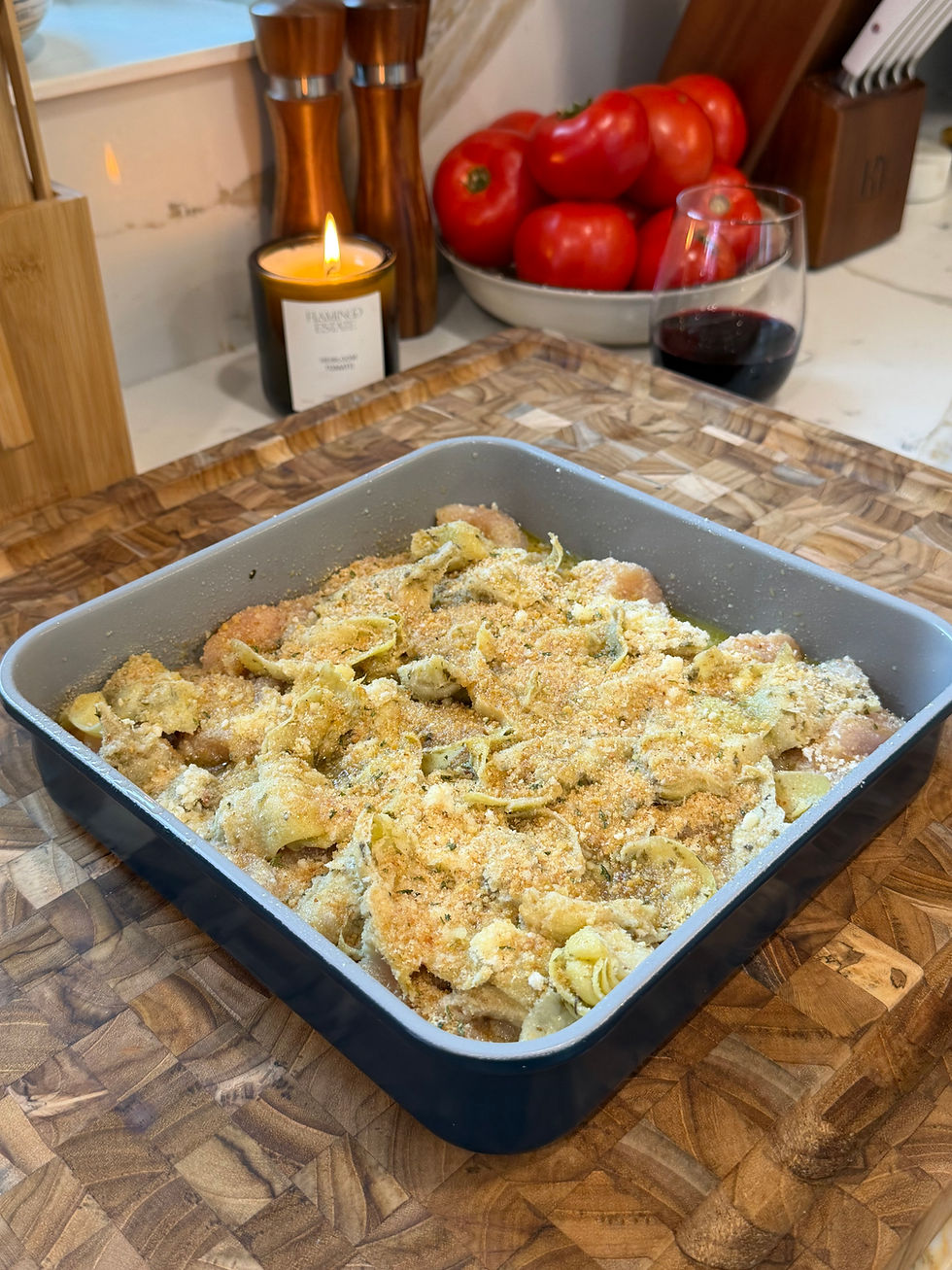 Overhead view of stuffed artichoke chicken in a baking dish with lemon slices and golden breadcrumbs.