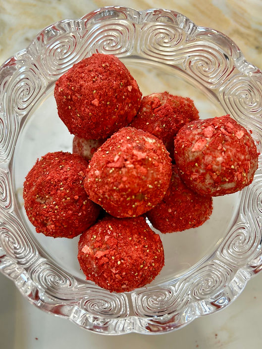 Close-up view of strawberry shortcake protein balls on a rustic wooden plate