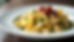 Close-up view of creamy farfalle pasta with peas and crispy pancetta on a white plate