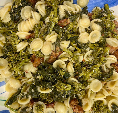 Close-up view of a skillet filled with spicy sausage and broccoli rabe, showing vibrant greens and browned sausage pieces