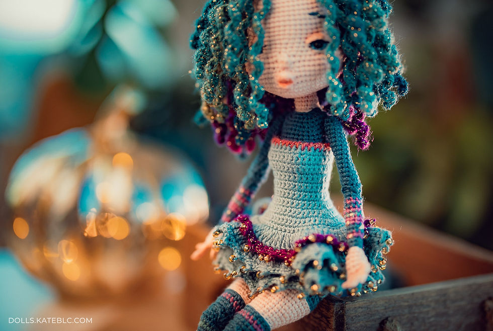 Crochet doll in the dress sitting on the box