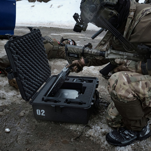 Airsoft player with rifle searches black pelican case