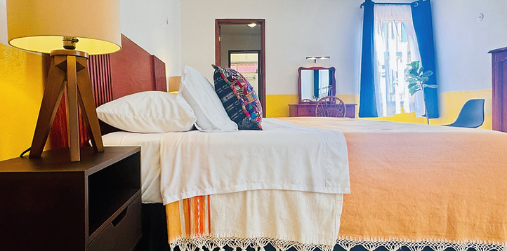 Bed in Habitación Amarilla at Los Colores de Mérida B&B featuring handmade Oaxaca textile blanket