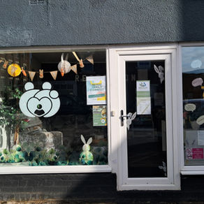 Storefront with Easter decorations, including a bear face and bunny bunting. Posters on door display "Nexus Family Connect" text. Bright and inviting.