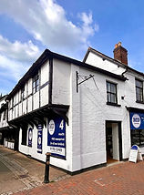A white 2-storey building with a blue banner on the front and side of the building.