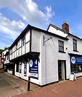 A white 2-storey building with a blue banner on the front and side of the building.